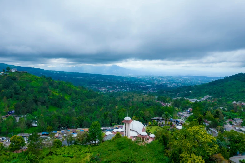 a hillside view with a city below a large cloud filled sky