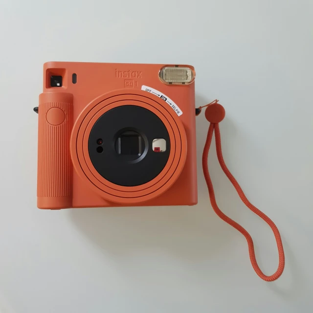 an orange camera is held up to show its inner body