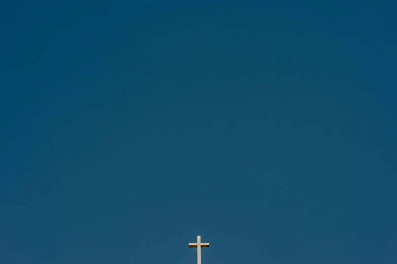 a white cross and blue sky with only one cloud