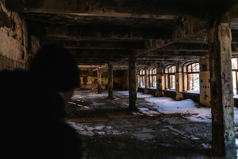 a po of a woman looking into the distance in an old rundown, dark building
