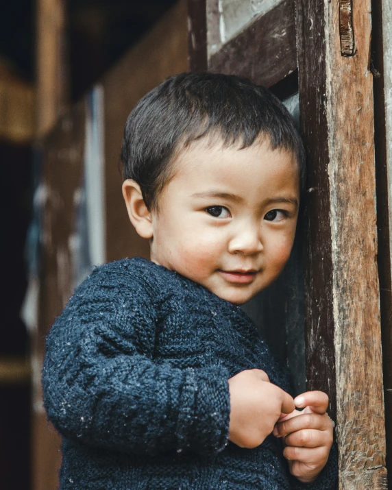 a boy stands near an open wooden door