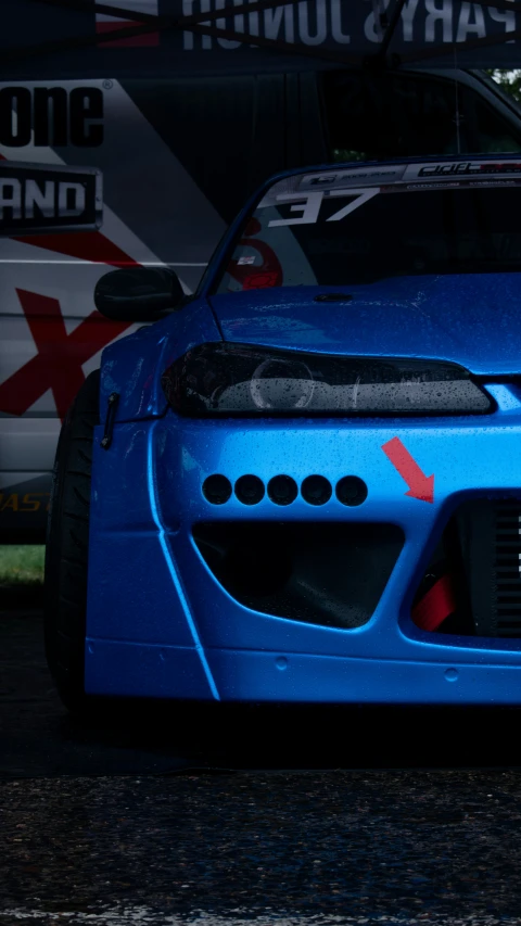the front of a blue racing car parked in the street