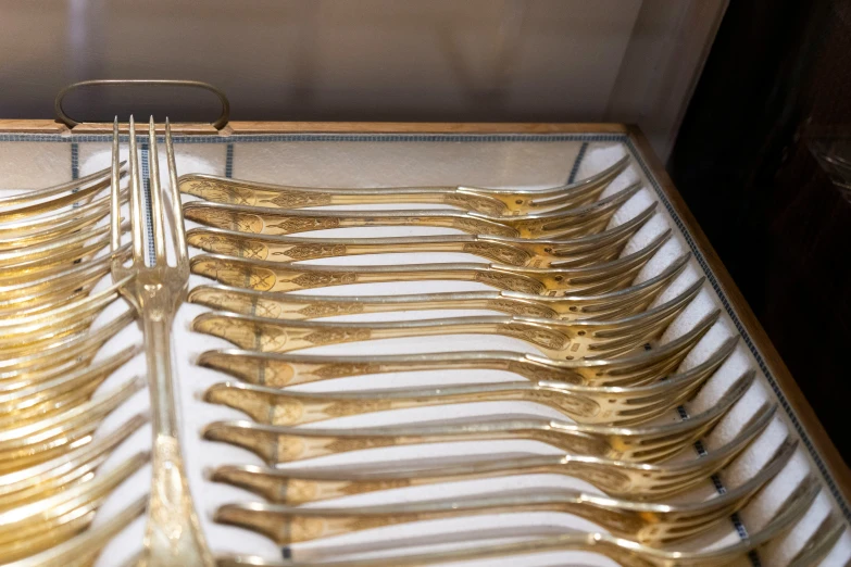 some gold forks lined up together on white plates