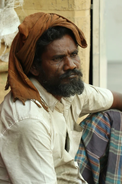 a man with a beard in a white shirt and a scarf