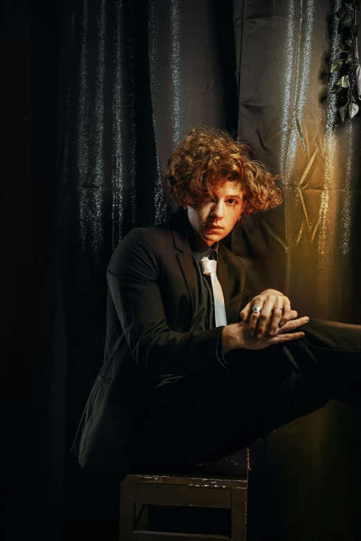 a man sitting next to a black backdrop with an open umbrella