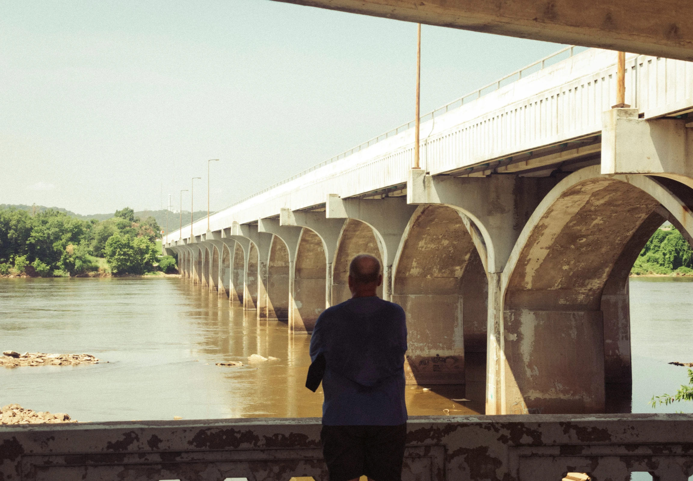 a man standing on top of a bridge looking at a river