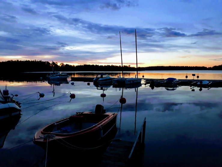 many small boats are in a lake under a sunset