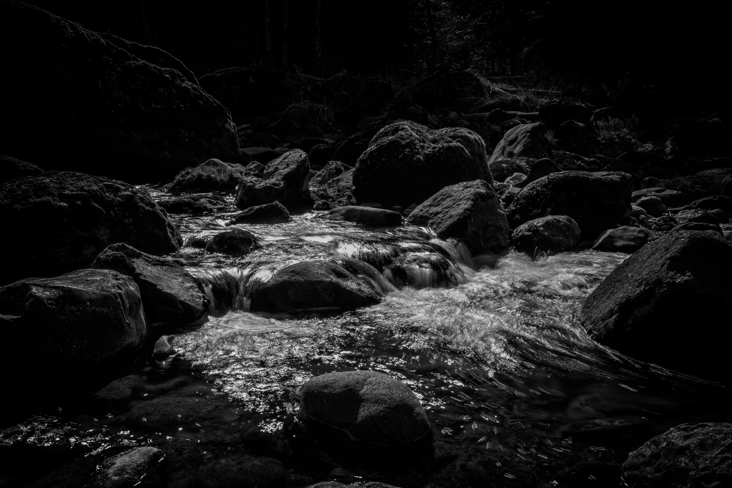 some rocks water grass and a hill