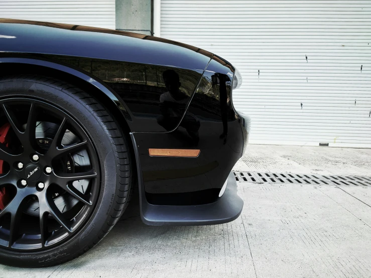 black car parked on a street with the front tire