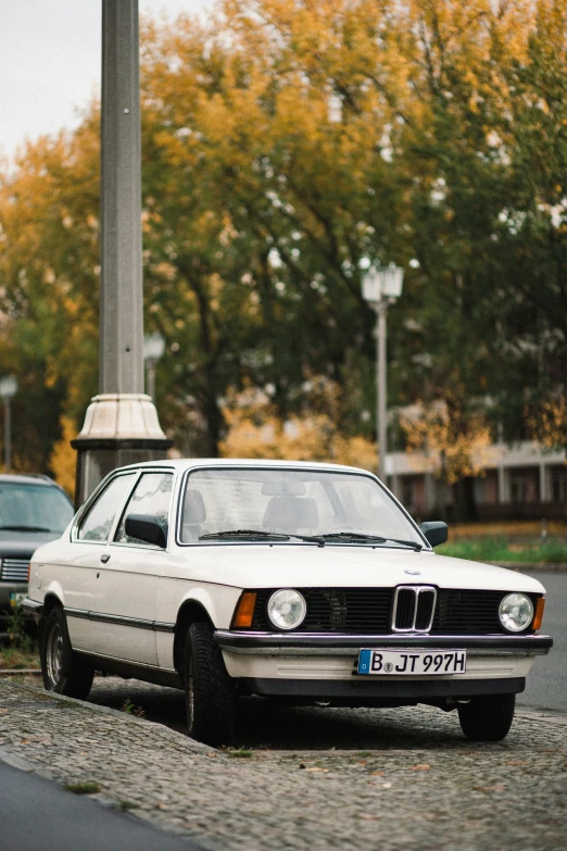 an old car parked on the street with some trees in the background