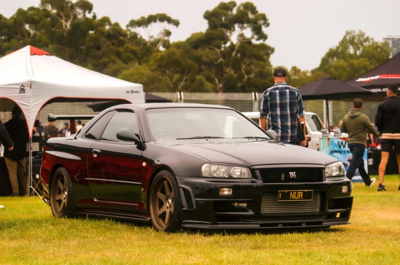 a dark colored honda car sits in the grass near a tent