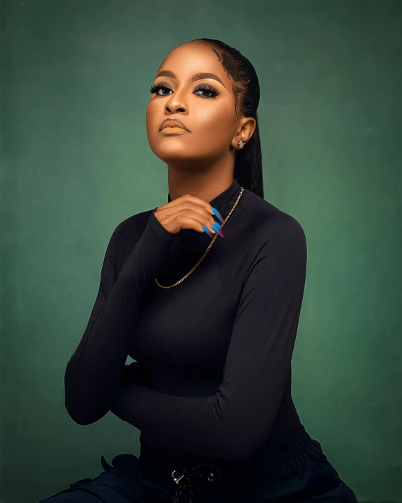 an african woman sitting on a stool in a black dress