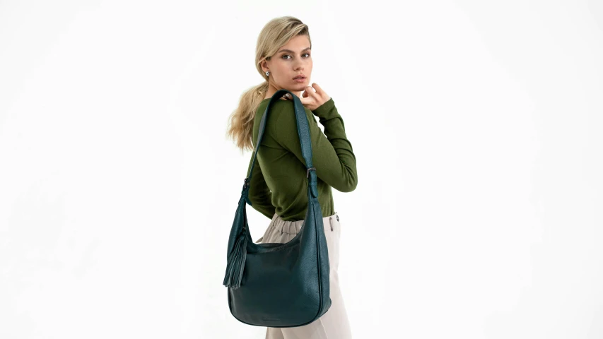 a woman wearing white pants holding a green purse