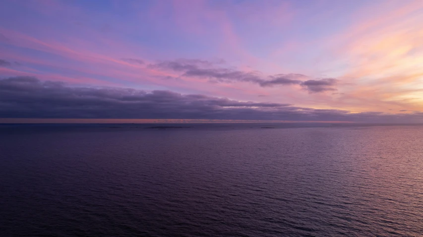 the ocean is full of purple clouds as it gets dark