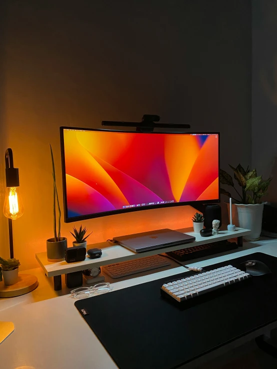 the desk has two computers on it and a lamp