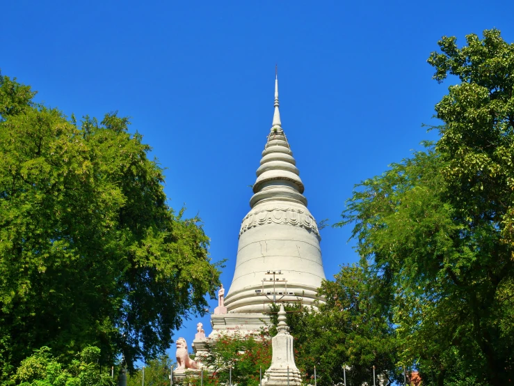 a white pagoda with green foliage next to trees