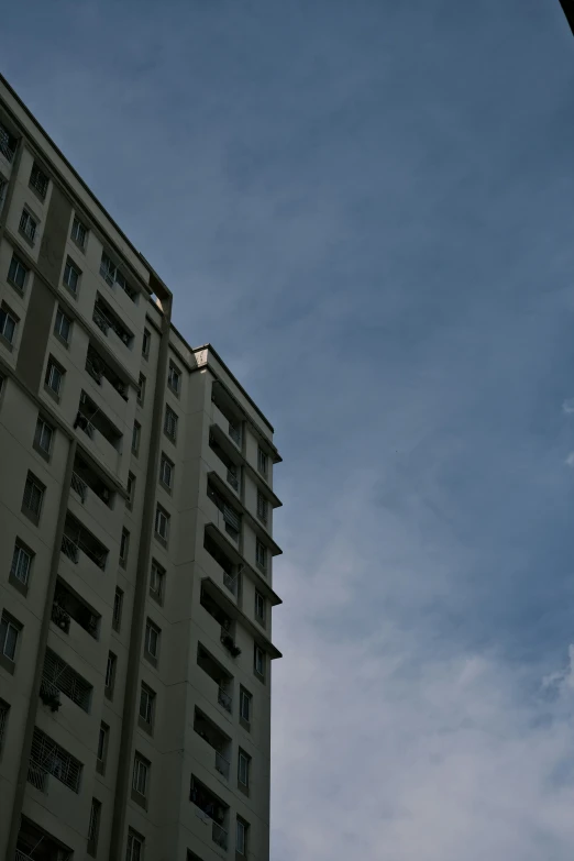 a high rise building with balconies is silhouetted against a cloudy sky