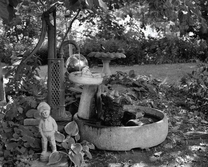 black and white po of a fountain in a garden with two stuffed animals