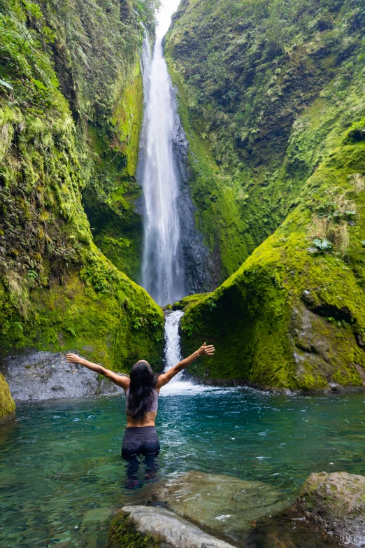 a person standing in the water next to a waterfall