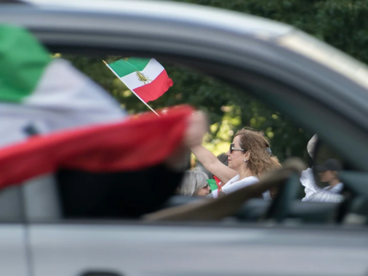 a person with a mexican flag waving from a car