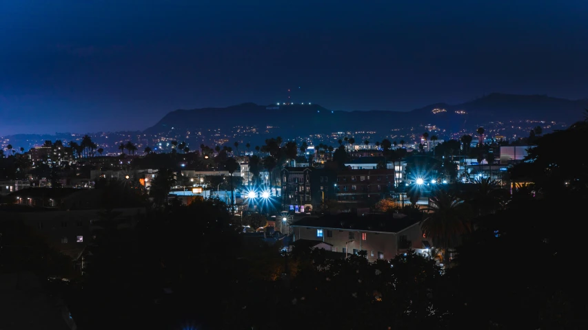 a cityscape is lit up in the night as a mountain is in the background