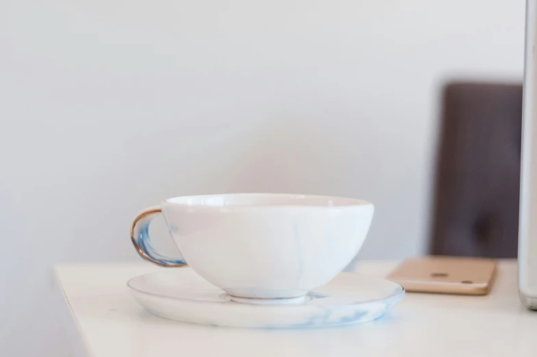 a white cup on a saucer with the side plates next to it