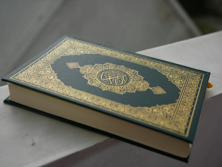 a large gold and blue book on top of a cement ledge