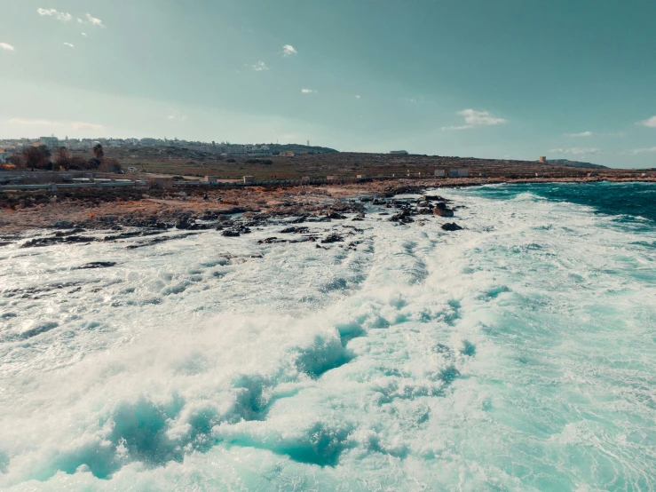 the ocean is rushing into the rocky shore