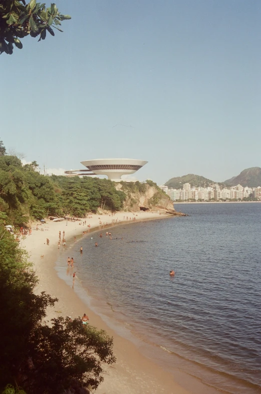 people are walking along the beach by the water