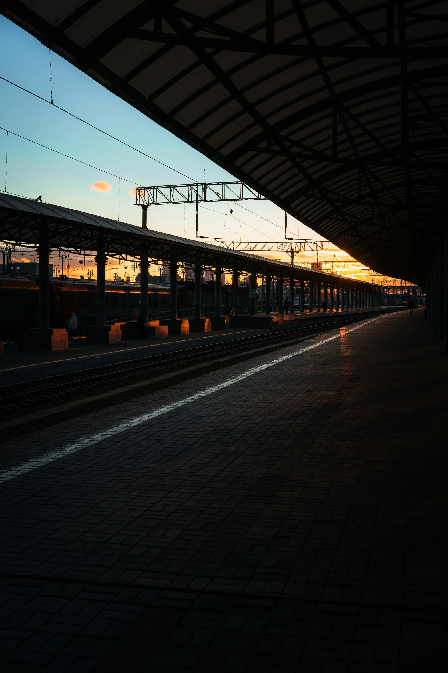 a train stopped at a very train station as the sun sets
