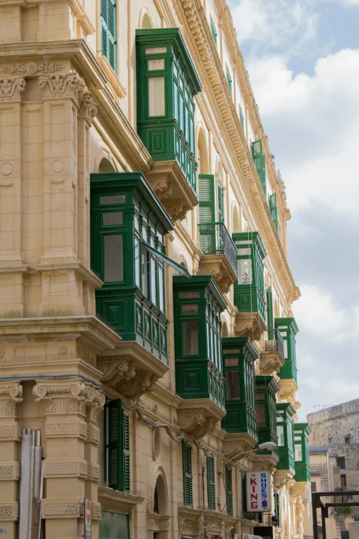 green and tan buildings with shutters on the balconies