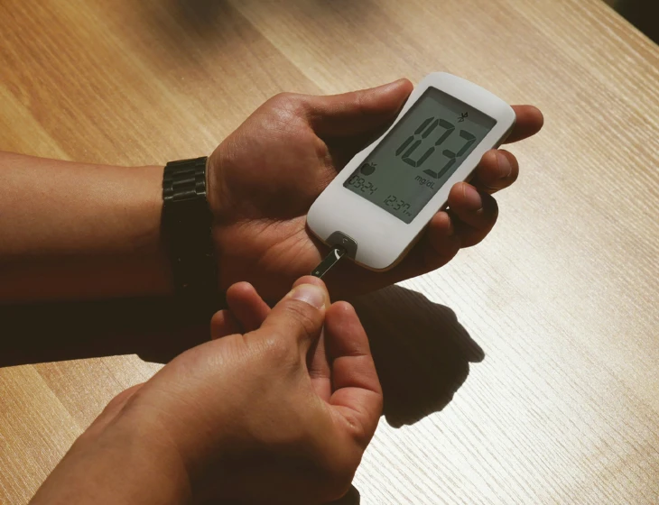 an open hand holding an alarm clock above a wooden table