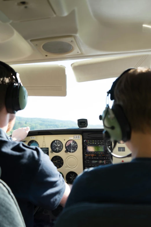 two pilots in an airplane with headsets and control ons