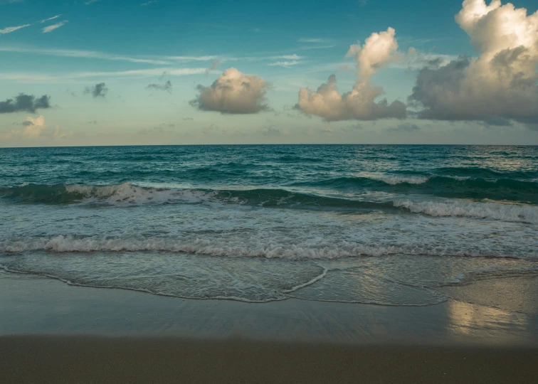 a beautiful beach is covered in waves and clouds