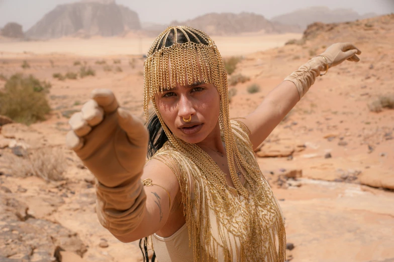 a woman dressed as a golden egyptian princess pointing at soing