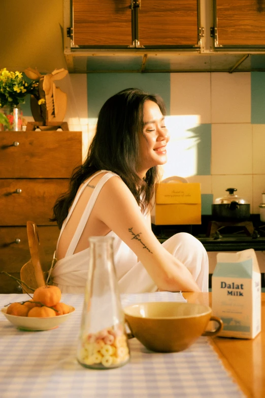 a woman sitting on the table in a kitchen