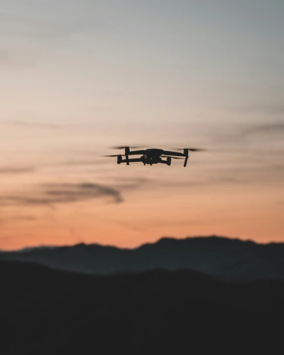 a small plane flying over some mountains at sunset