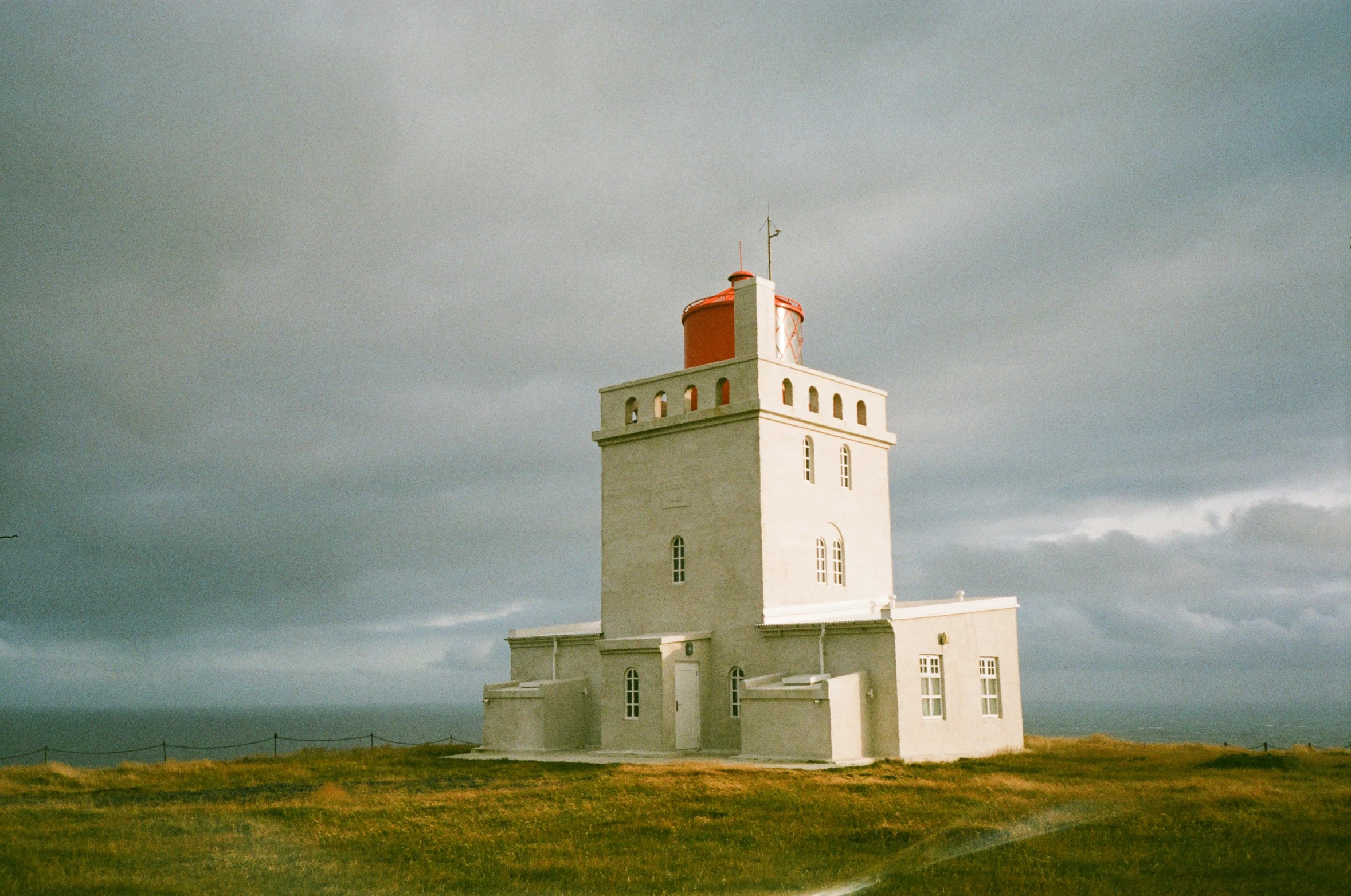 there is a white tower with a red roof and some bushes