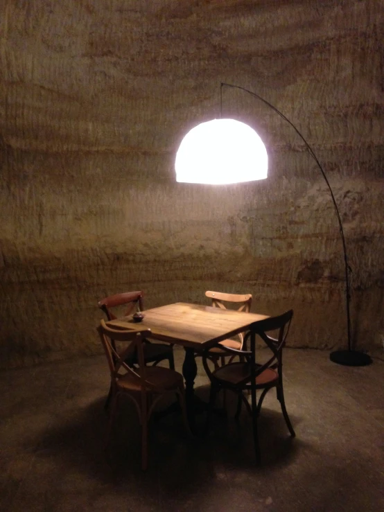 a table with a chair and lamp is near the wall