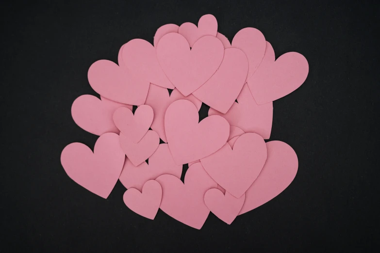 pink hearts laid out on a black background