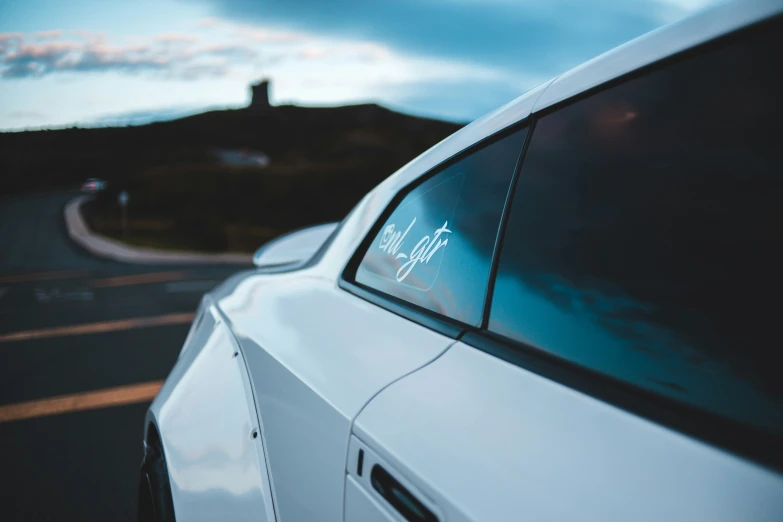 the side of a white car parked near a large hill