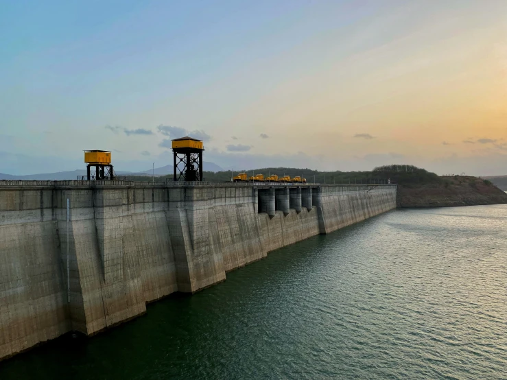 two concrete structures near water and hills at sunset