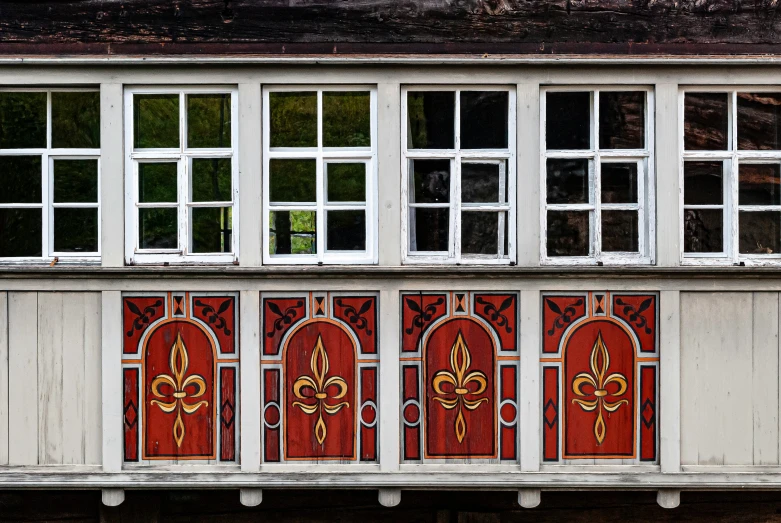 close up of two white wooden windows with red painted doors