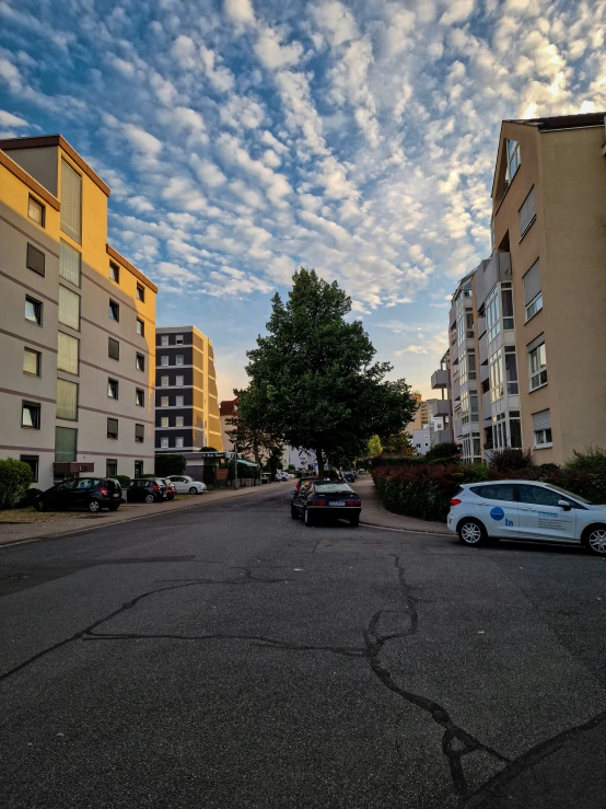 cars parked at the side of a road between apartment buildings