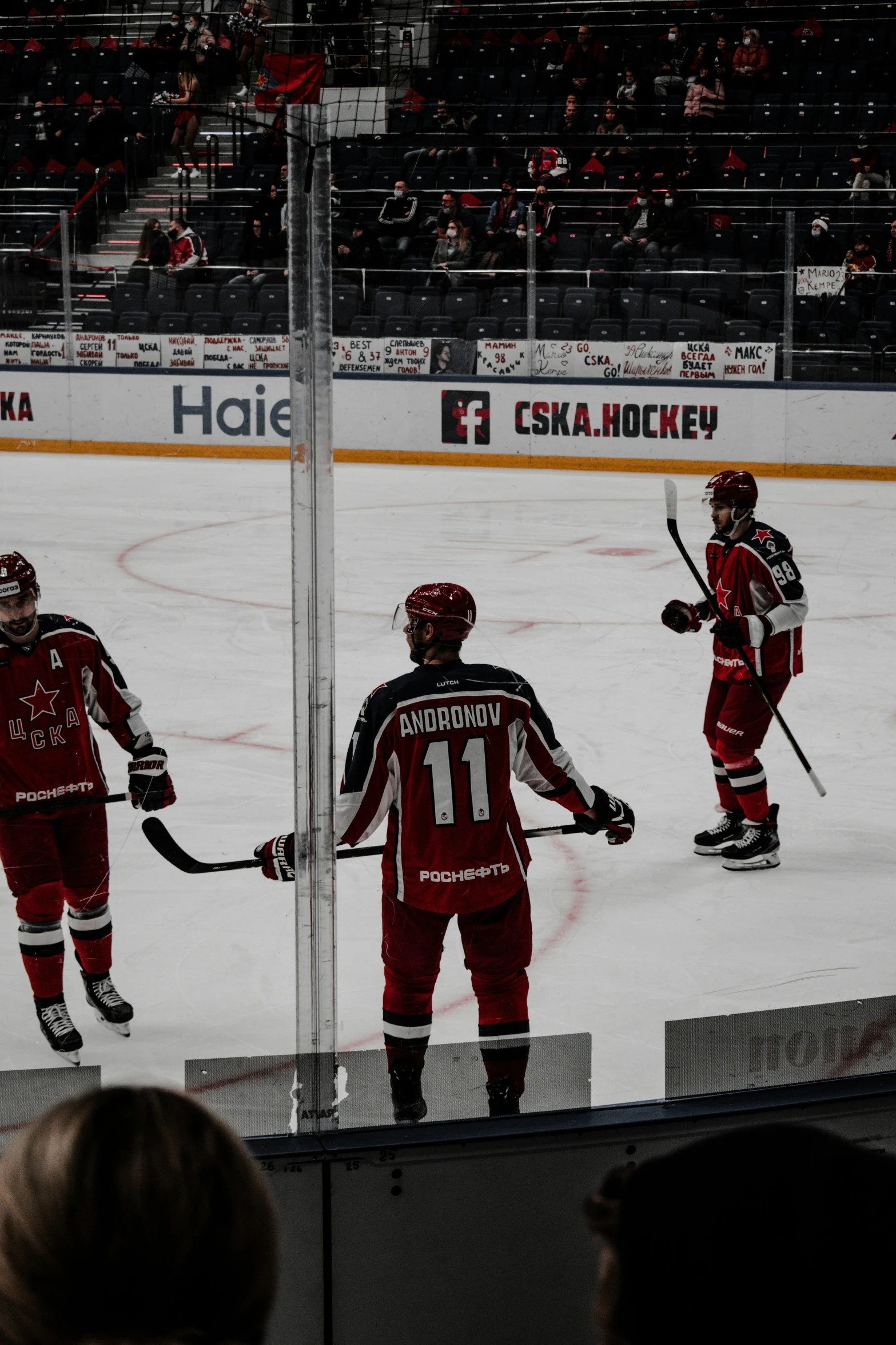 a man stands in front of three men on an ice rink