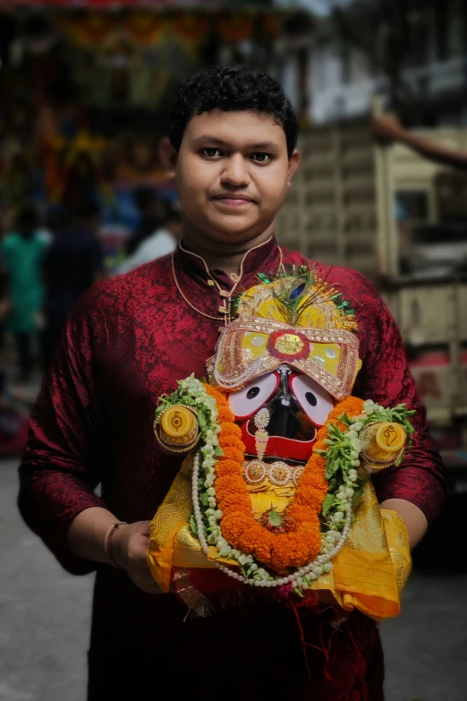 man in red traditional attire holding up a idol