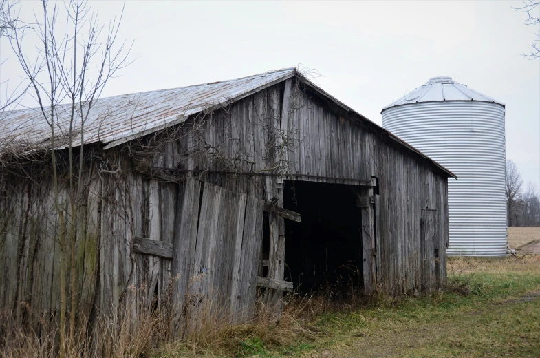 an old weathered barn and silo in a field