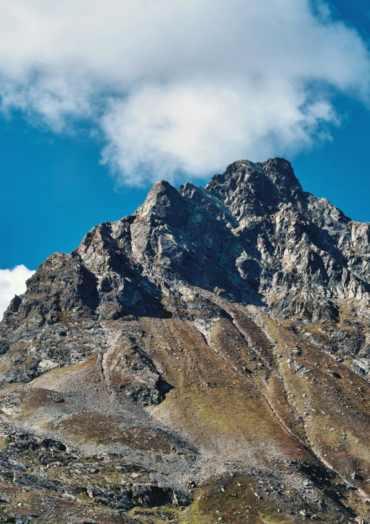 a mountain on a sunny day with many clouds in the sky