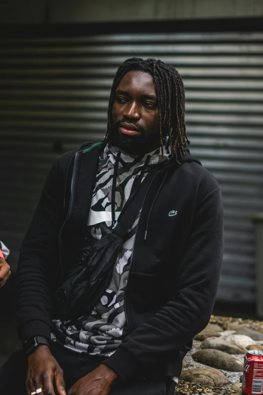 a black man sitting outside near some cans