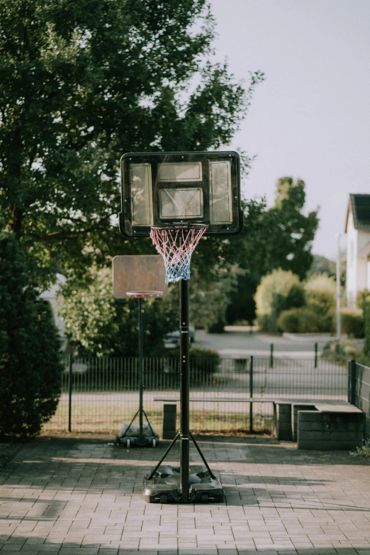 basketball hoop and net in front of trees on cement patio
